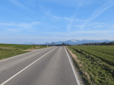 Bergpanorama mit einem Rennradfahrer im Vordergrund im Frühling